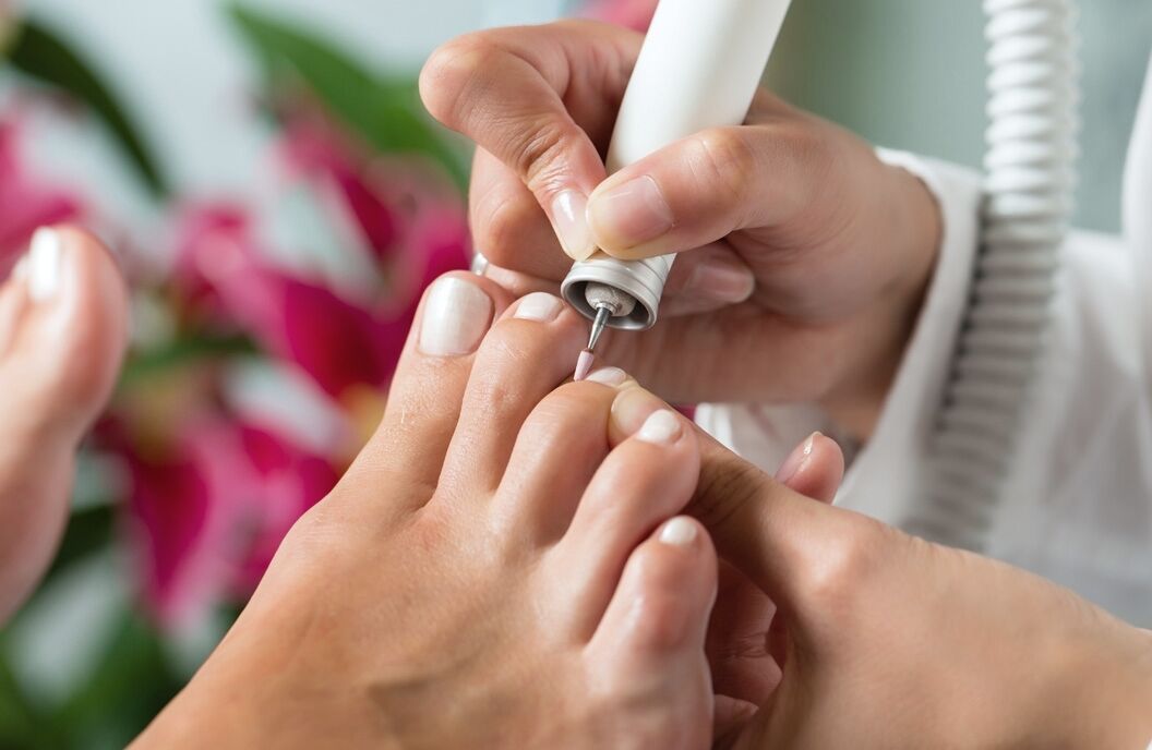Pedicure behandelt de nagels van een voet